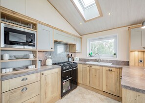 A modern kitchen with a built-in microwave, stove, and oven, wooden cabinets, and a window with a view.