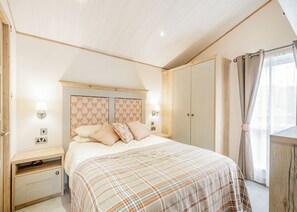 Een slaapkamer met een bed, nachtkastjes, een kledingkast en een raam met gordijnen.