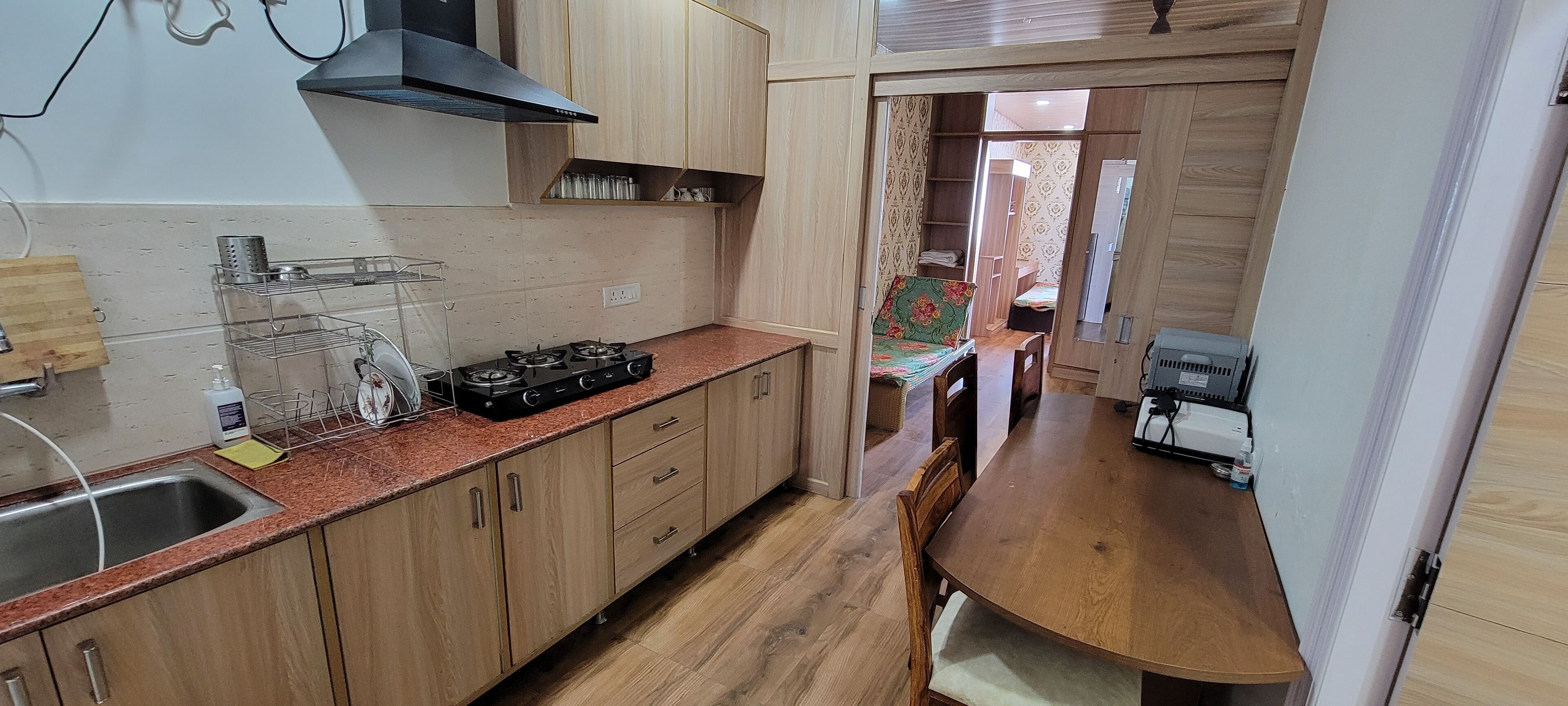 A compact kitchen with wooden cabinets, a gas stove, and a dining area with a table and chairs.