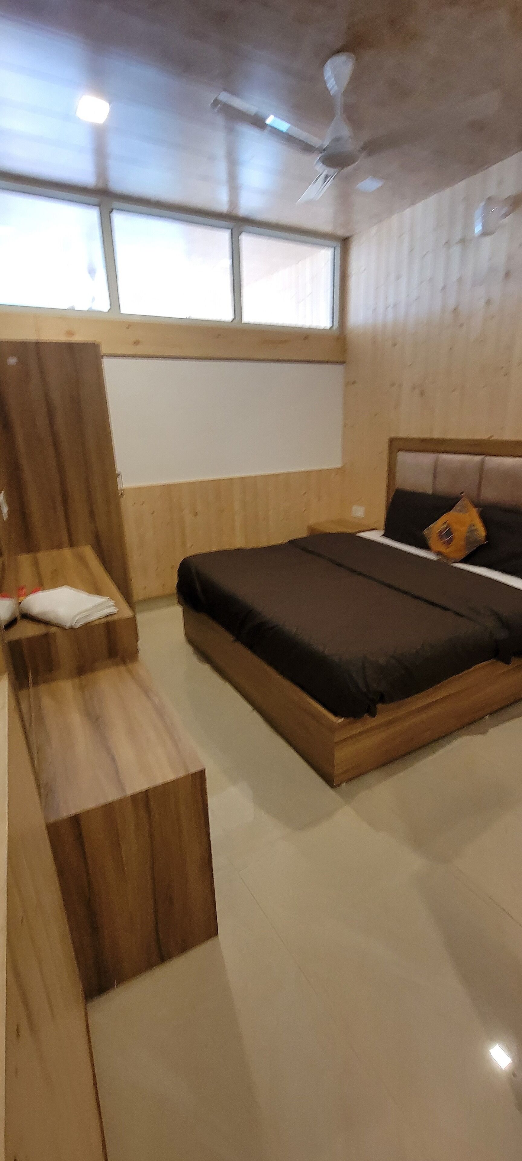Une chambre à coucher avec un lit, un banc en bois et un ventilateur de plafond.