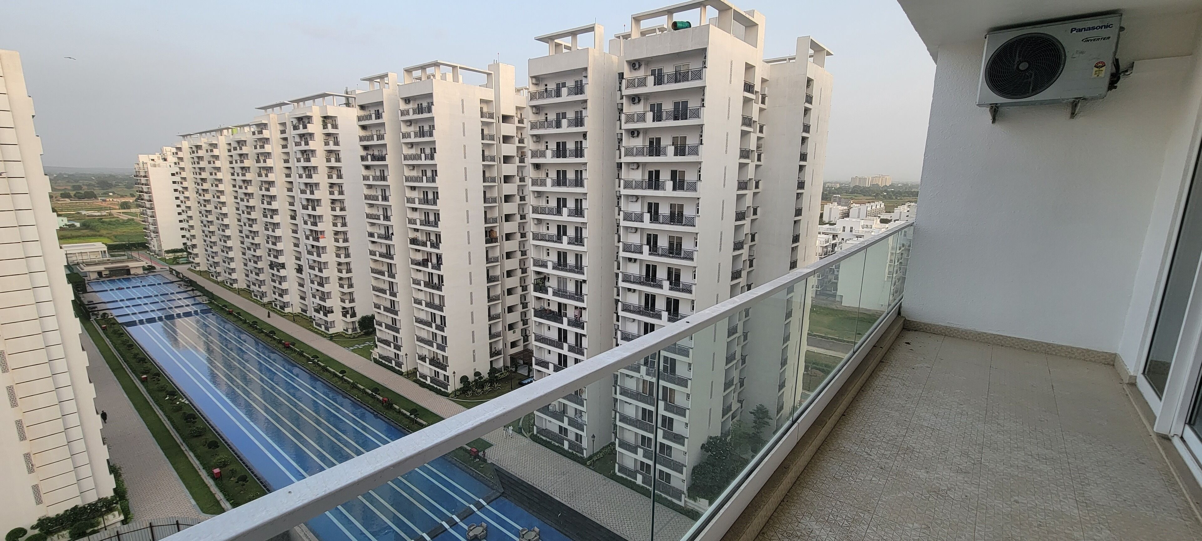 A high-rise residential building with multiple balconies, a swimming pool, and a Panasonic air conditioning unit.
