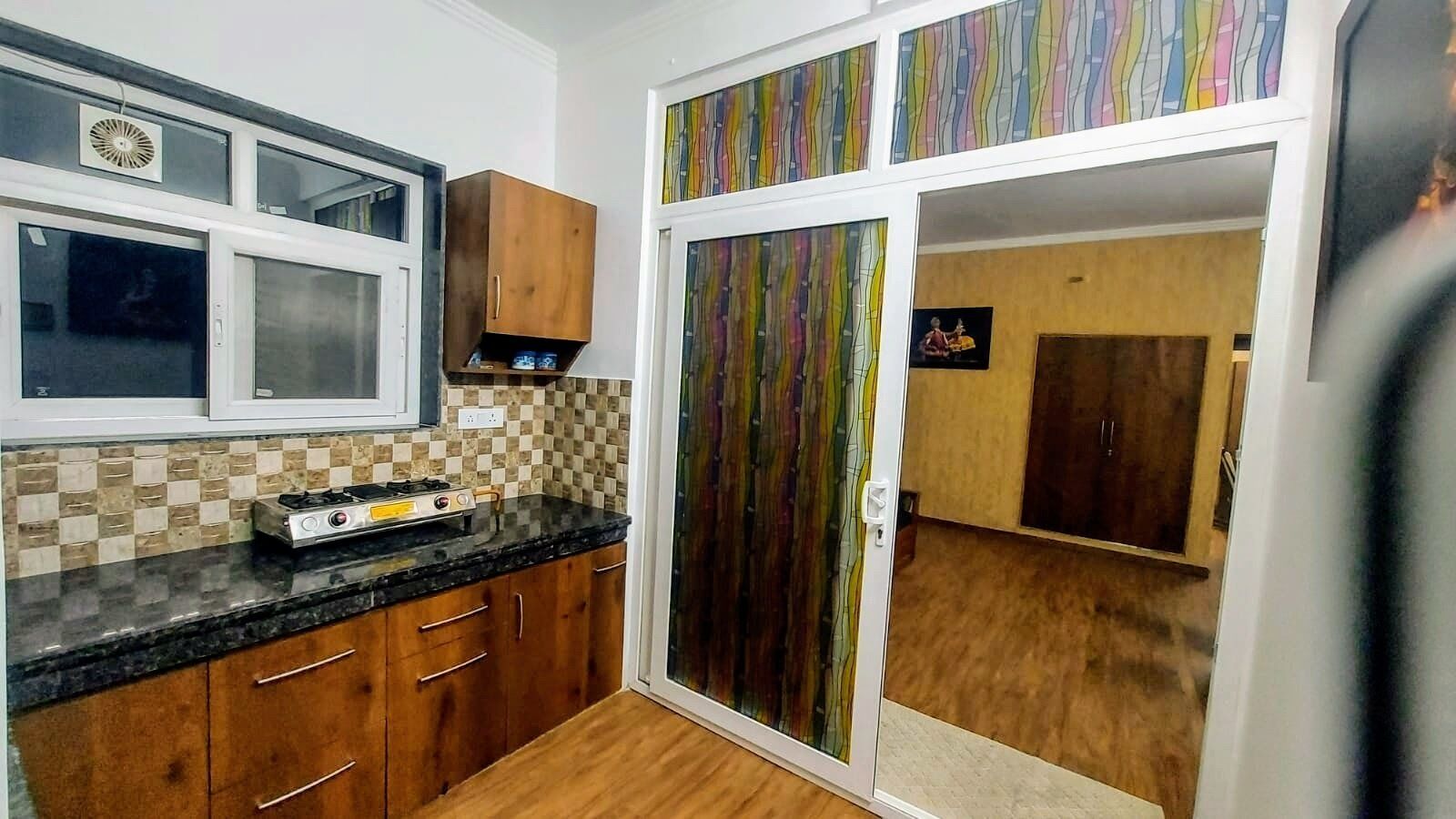 Cocina compacta con estufa a gas, armarios de madera y salpicadero de cuadros.