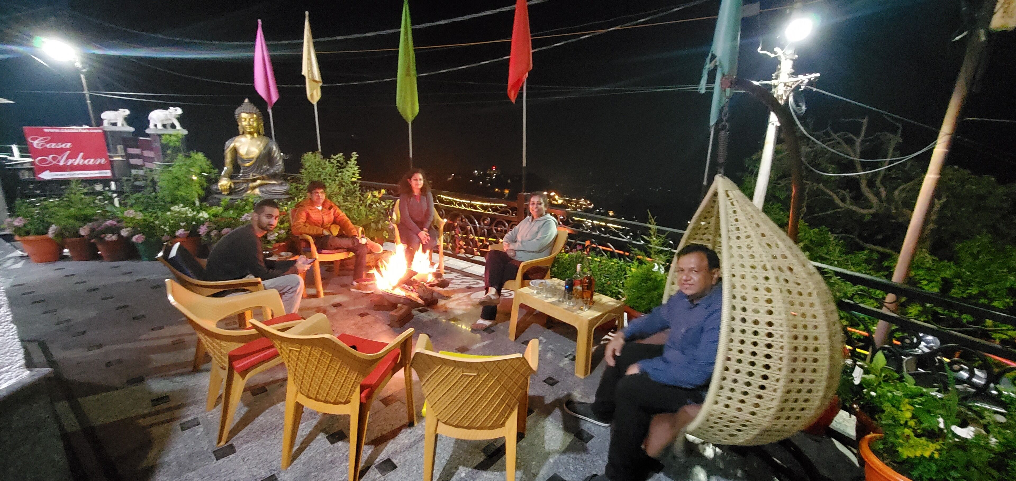 A group of people seated around a fire pit with a Buddha statue in the background.