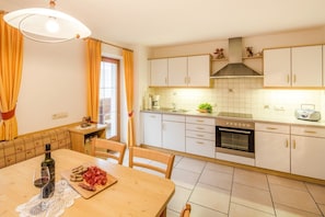 Una cocina con armarios blancos, una estufa y un comedor con una mesa lista para dos.