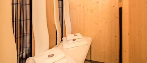 A wooden spa room with two beds, each with a white towel and a heart-shaped pillow.