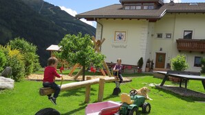 Un'area giochi con un'altalena, un trattorino e un cane.