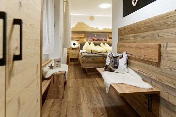 Una habitación acogedora con paredes y muebles de madera, una cama con almohadas, una mesita de noche y un cuadro colgado en la pared.