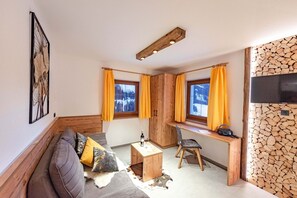 Una habitación acogedora con un banco de madera, un escritorio, una silla, un sofá y un televisor.
