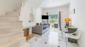 A modern interior with a staircase, a sofa, a TV, and a dining area. - Doliva John Apartment with Private Jacuzzi, Mountain View and Air Conditioning (Corfu)