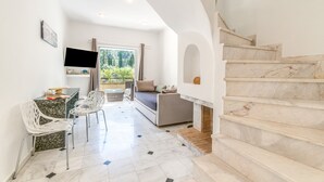 A modern interior with a sofa, chairs, a TV, and a staircase. - Doliva Erietta Apartment with Private Pool, Mountain View, Wi-Fi & Air Conditioning (Corfu)