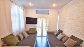 A room with two sofas facing each other, a flat-screen TV mounted on the wall, and a window with curtains. - Doliva Studio Apartment with Private Pool, Mountain View, Wi-Fi, and Air Conditioning (Corfu)
