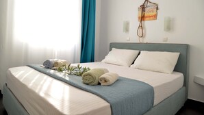 A neatly made bed with rolled towels, a blue blanket, and a wall-mounted light fixture. - Doliva Studio Apartment with Private Pool, Mountain View, Wi-Fi, and Air Conditioning (Corfu)
