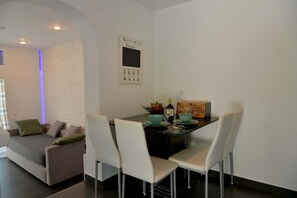 A modern living room with a sofa, dining table, and chairs. - Doliva Studio Apartment with Private Pool, Mountain View, Wi-Fi, and Air Conditioning (Corfu)