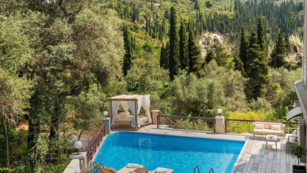 A pool area with lounge chairs, a table, and a view of a mountainous landscape. - Doliva Studio Apartment with Private Pool, Mountain View, Wi-Fi, and Air Conditioning (Corfu)