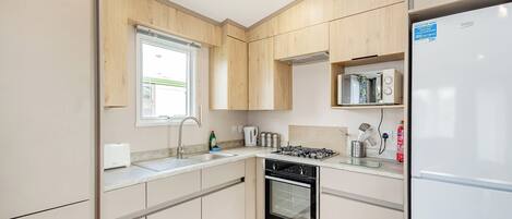 A modern kitchen with wooden cabinets, a built-in oven, a gas stove, and a refrigerator.