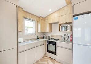 A modern kitchen with wooden cabinets, a built-in oven, a gas stove, and a refrigerator. - 2 bedroom accommodation in Kirkcudbright (Kirkcudbright)