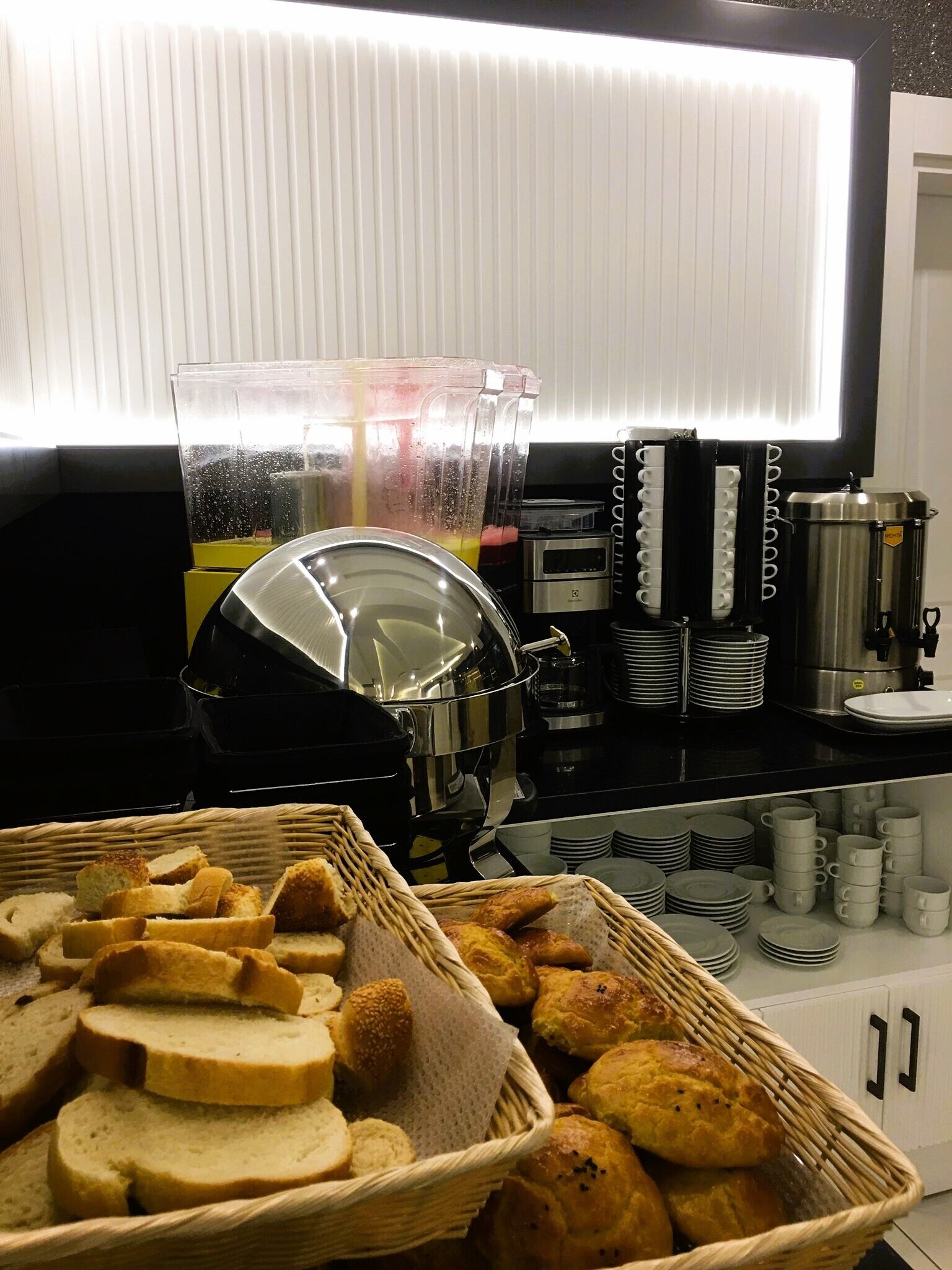 A buffet setup with bread, pastries, and a coffee station.