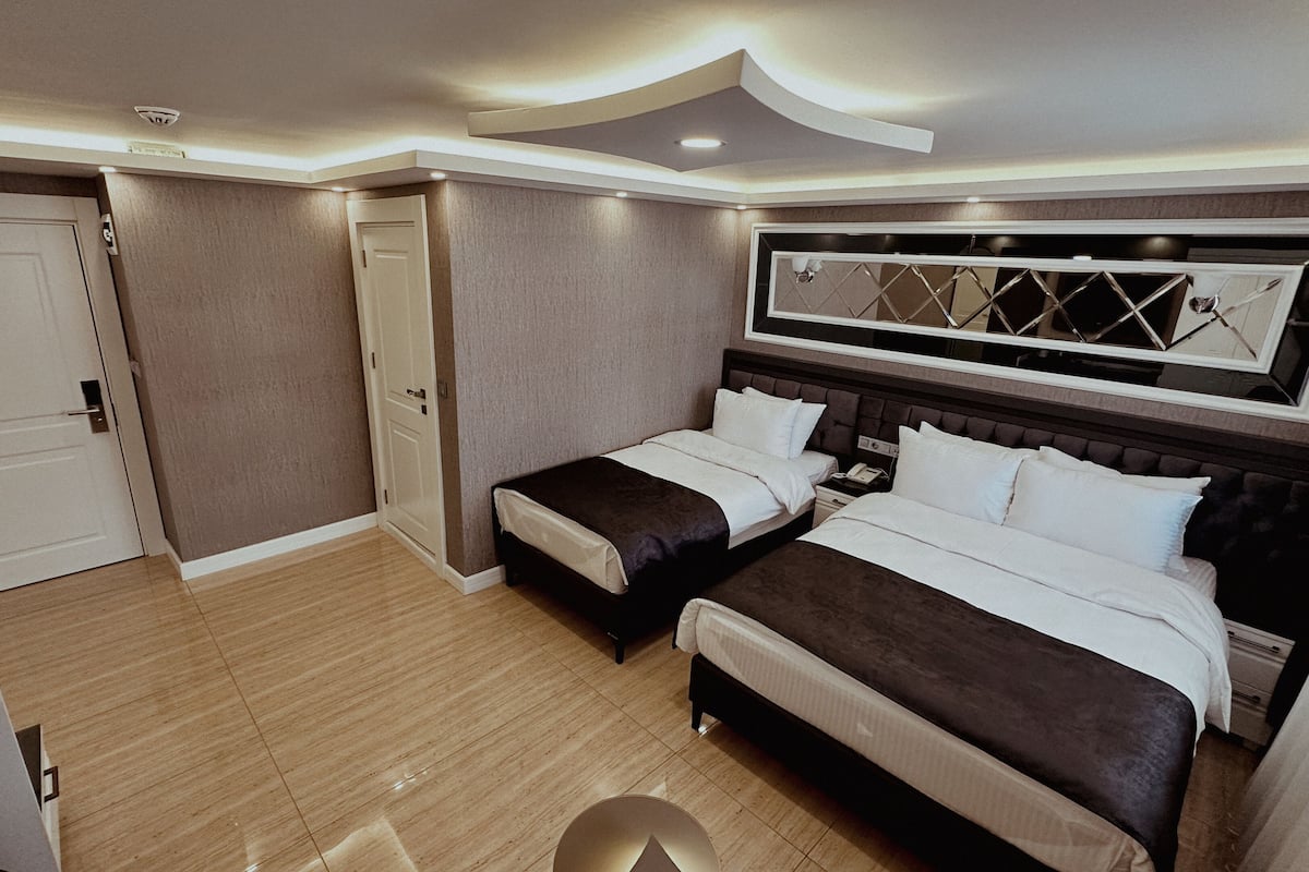 A hotel room with two beds, a large mirror, and a ceiling light fixture.