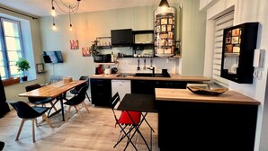 A modern kitchen with a central island, black cabinetry, and a pendant light. - Appartement Proche Cathédrale (Albi)