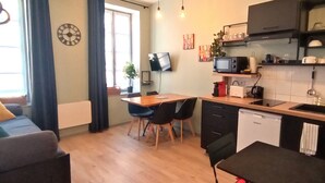 A compact living space with a dining area, kitchenette, and a TV mounted on the wall. - Appartement Proche Cathédrale (Albi)
