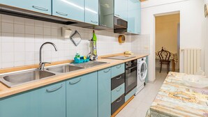 Une cuisine équipée d’un évier, d’une cuisinière et d’un lave-linge.