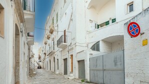 Une ruelle pavée bordée de bâtiments blancs dotés de balcons et de volets.
