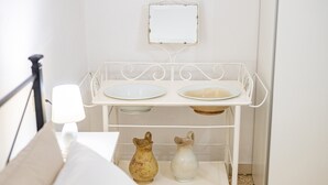 Une étagère en métal blanc, avec deux assiettes blanches et deux pichets en céramique.