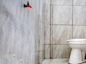 A bathroom with a white toilet, a red faucet, and tiled walls. - OYO Life 92919 Kost Wijaya Kusuma Lake Syariah (Madiun)