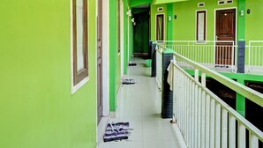 A corridor with green walls and white railings, leading to multiple rooms with wooden doors. - OYO Life 92919 Kost Wijaya Kusuma Lake Syariah (Madiun)