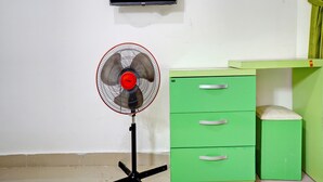 A room with a standing fan, a green filing cabinet, and a mounted television. - OYO Life 92919 Kost Wijaya Kusuma Lake Syariah (Madiun)