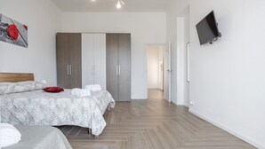 A modern bedroom with a bed, wardrobe, and a mounted TV.