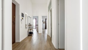 A hallway with white walls, wooden flooring, and doors leading to rooms.