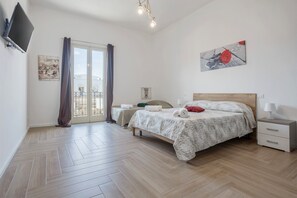 Une chambre avec un lit, des tables de chevet, une télévision et un balcon avec vue.