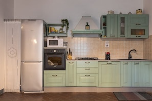 Uma cozinha equipada com frigorífico, forno, micro-ondas, pia e armários verde-claros.