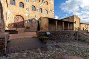 Un edificio storico con un'ampia porta in legno, pareti in pietra e un cortile lastricato.