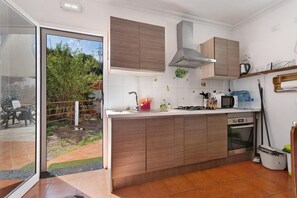 A kitchen with a built-in stove, microwave, and oven, a sliding glass door leading to a patio, and a small outdoor area with a fence and plants.
