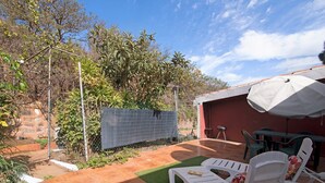 Une terrasse avec des meubles d’extérieur, un espace salon abrité et un jardin agrémenté d’une clôture et de plantes.