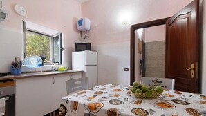 Une cuisine avec une fenêtre, un four à micro-ondes, un réfrigérateur, un évier et une table recouverte d’une nappe.