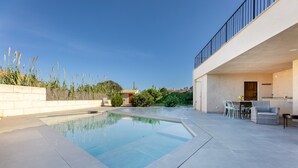 Une piscine à l’eau d’un bleu limpide, entourée d’une terrasse dallée.