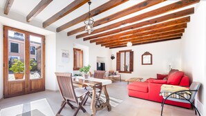 Un vaste espace de vie doté d’un plafond en bois, d’un canapé rouge, d’une table à manger avec des chaises et d’une vue dégagée sur l’extérieur grâce à une porte vitrée.