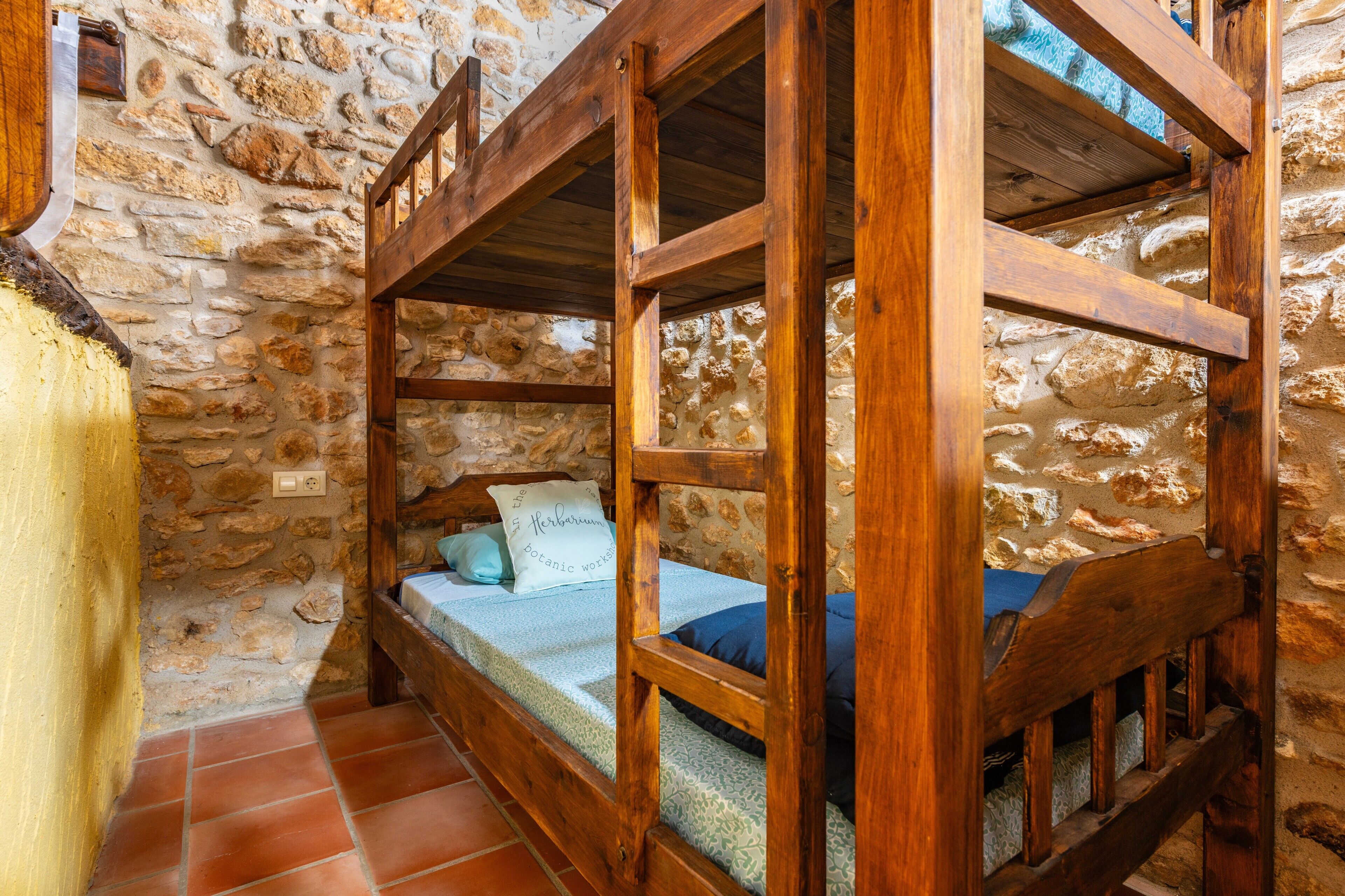 A rustic stone wall interior with a wooden bunk bed and a small window.