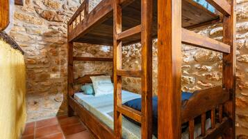 A rustic stone wall interior with a wooden bunk bed and a small window.