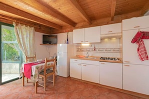 A kitchen with white cabinets, a gas stove, and a television mounted on the wall.