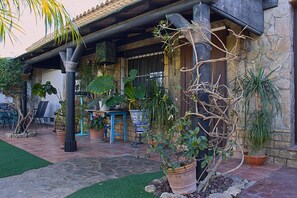 A covered outdoor area with a stone wall, potted plants, and a blue table.