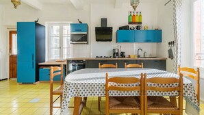 A kitchen with blue cabinets, a microwave, a stove, and a dining table with chairs.