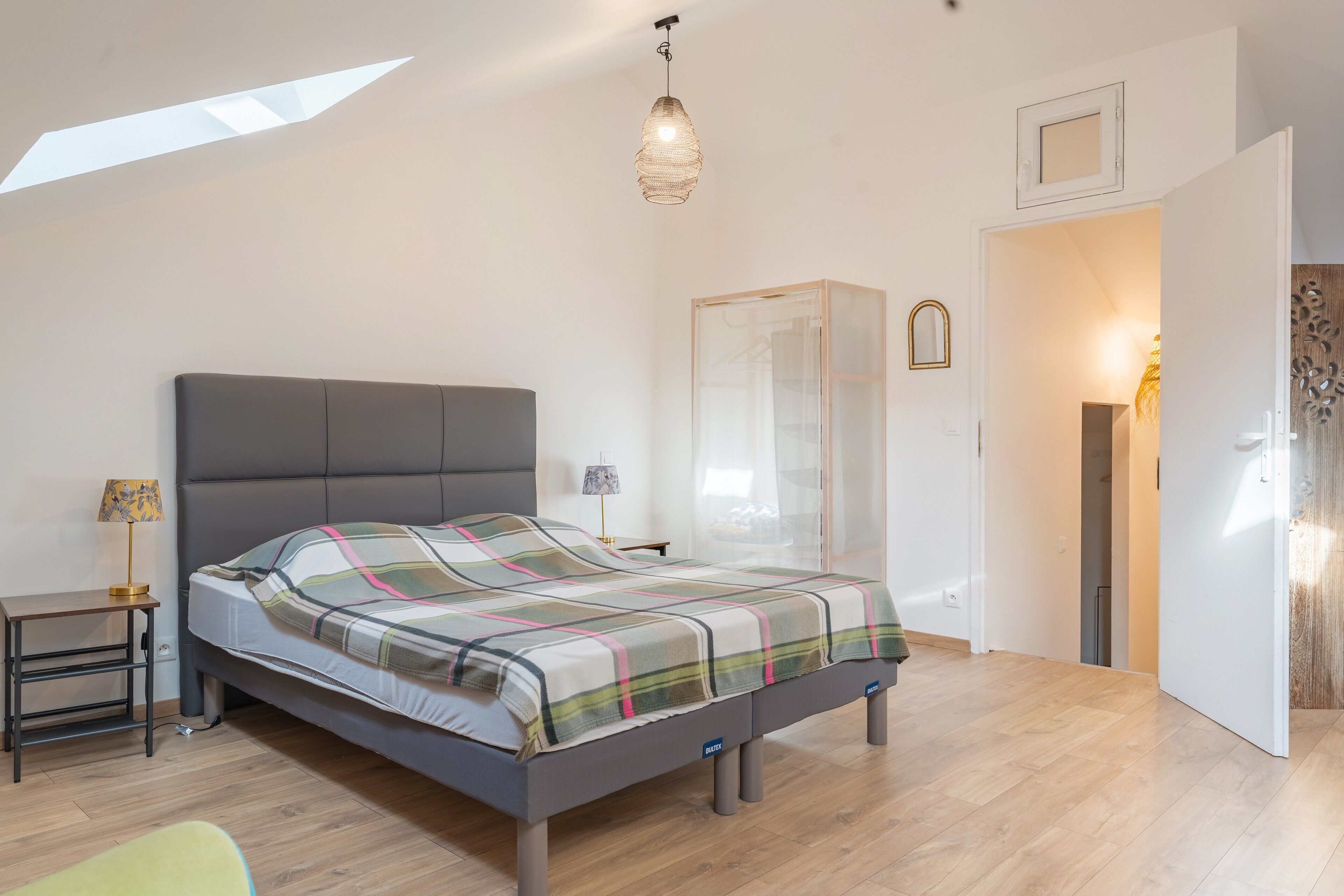 Une chambre à coucher moderne, avec un lit, une table de chevet, une lampe et une vue sur l’extérieur.