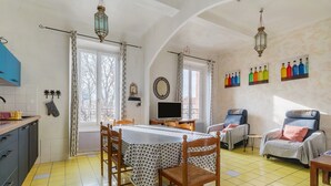 A dining area with a table and chairs, a television, and a seating area with a chair and a table.