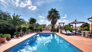 A swimming pool with lounge chairs and potted plants.