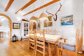 Un espace repas avec des meubles en bois, des luminaires suspendus et des œuvres d’art murales.