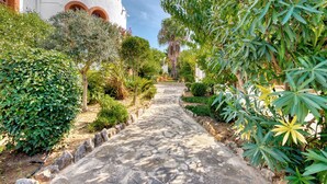 A stone pathway leading to a white building with arched windows.